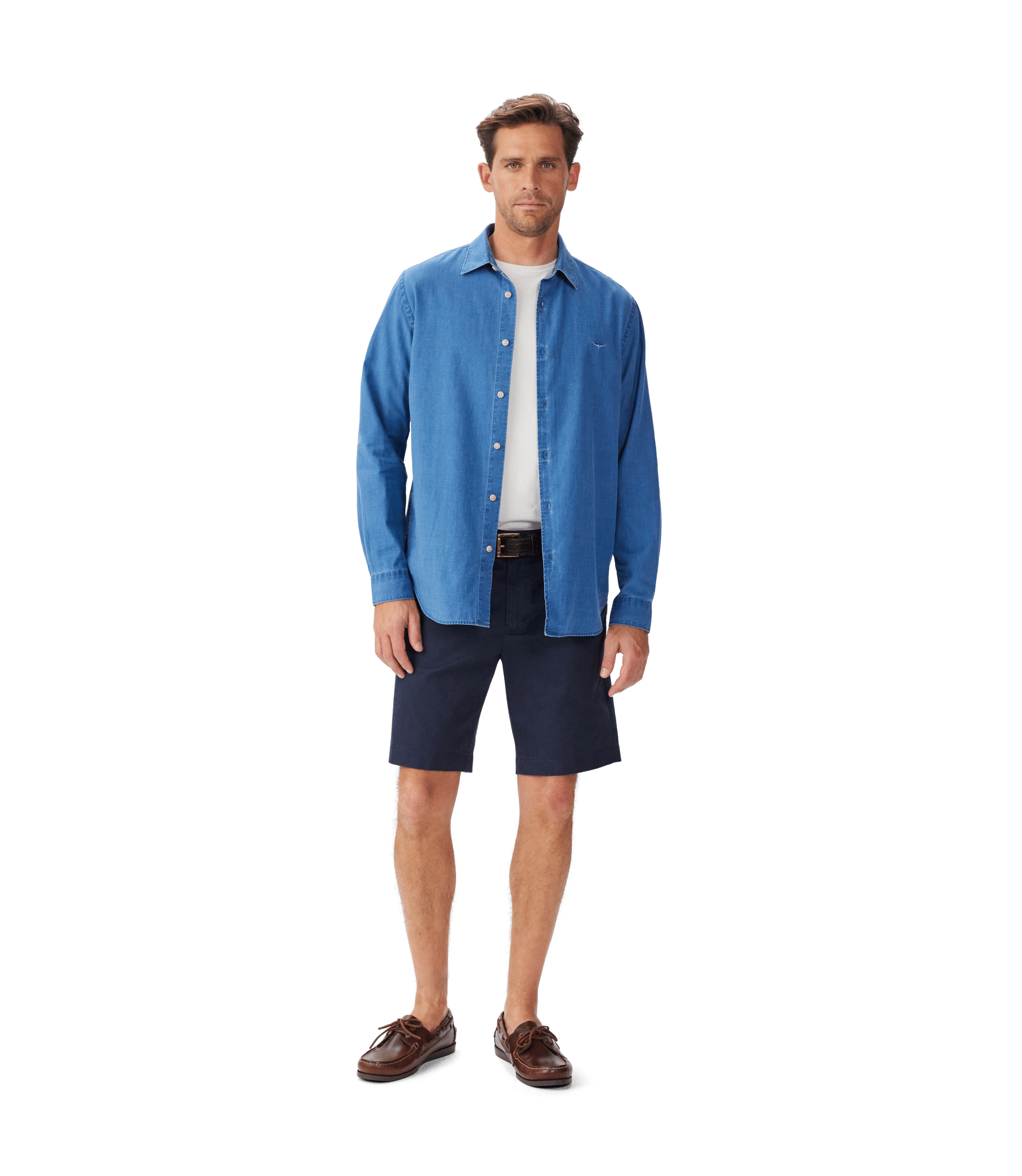A man stands facing forward, wearing a blue button-up shirt over a white t-shirt, navy shorts, a brown belt, and brown boat shoes against a plain white background.