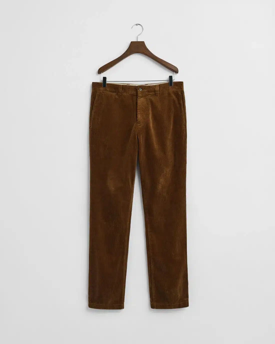 A pair of brown corduroy pants hanging on a wooden hanger against a plain white background.