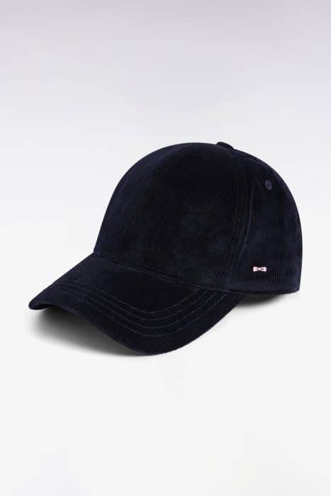A navy blue corduroy baseball cap with a curved brim, displayed against a plain white background. There is a small metallic detail on the side of the cap.