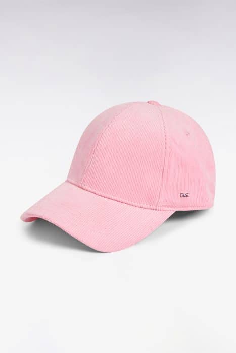 A pink corduroy baseball cap with a curved brim, displayed on a light, gradient background. A small metallic logo tag is visible on the side of the cap.
