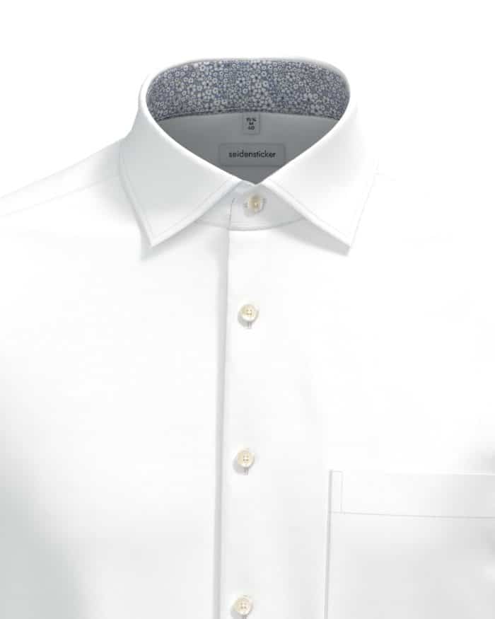 A white dress shirt with a pointed collar, visible white buttons, a chest pocket, and a contrasting inner collar lining featuring a blue and white floral pattern.