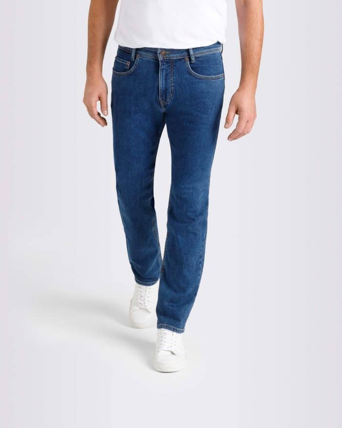 A person wearing a white T-shirt, blue jeans, and white trainers is standing against a plain light background. The photo is cropped at the shoulders and does not show the person's face.