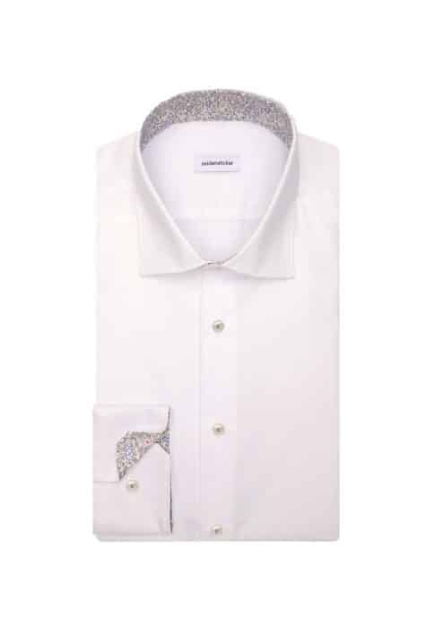 A neatly folded white dress shirt with a spread collar, featuring a floral-patterned inner collar and inner cuff, displayed on a plain white background.