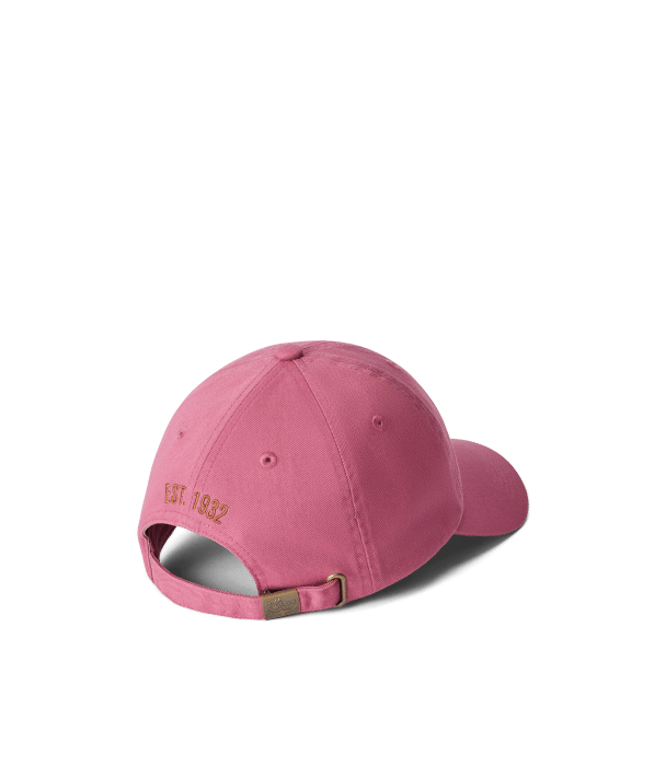 A pink baseball cap viewed from the back, featuring an adjustable strap with a metal buckle and the text E.S.T. 1832 embroidered in gold above the opening.