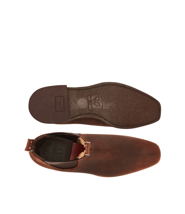 Top view of a pair of brown leather dress boots, showing the sole of one boot and the upper part of the other, with stitching detail and a pull tab visible.