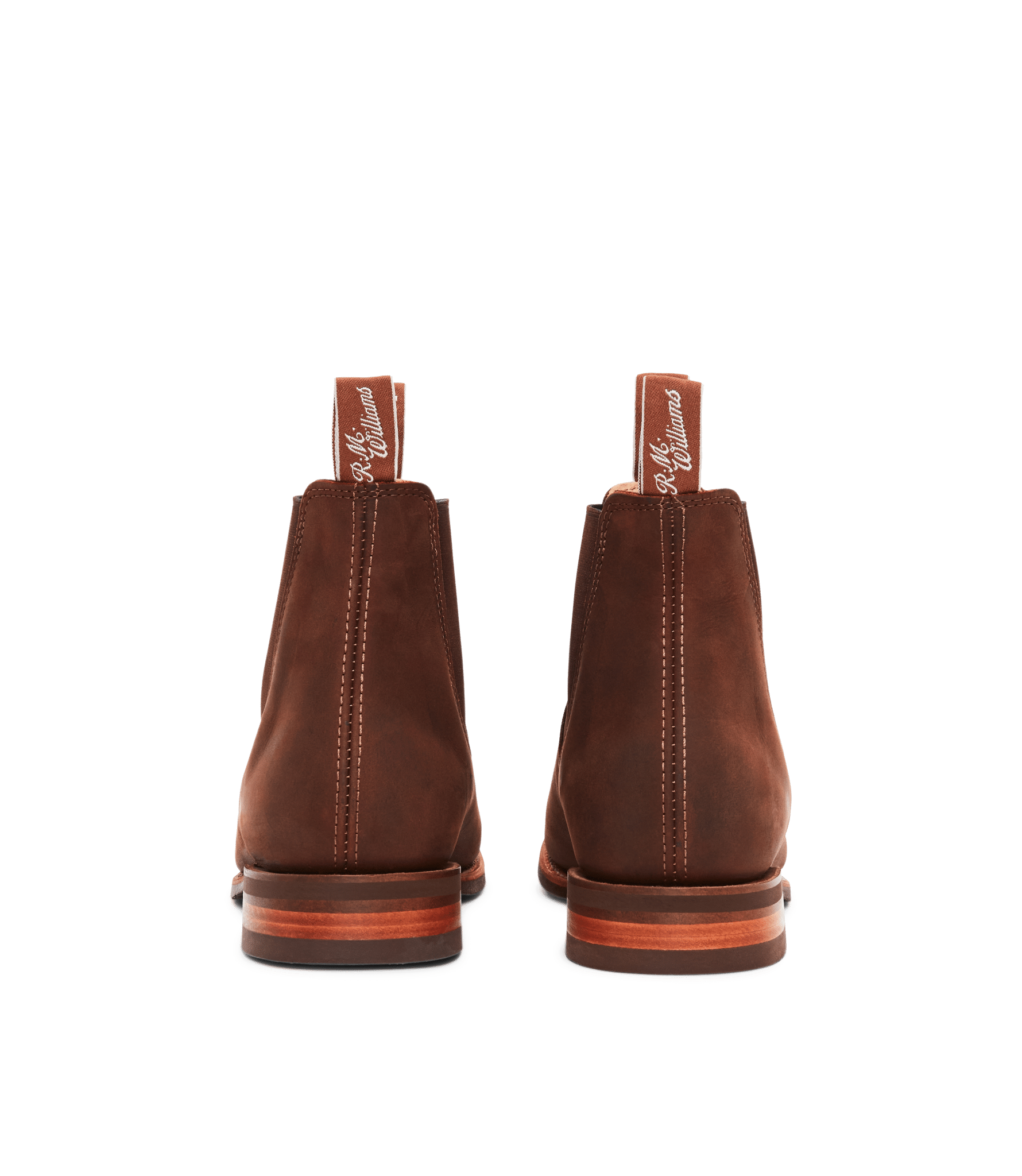 A pair of brown leather Chelsea boots viewed from the back, showing pull tabs with white script and visible stitching down the centre.