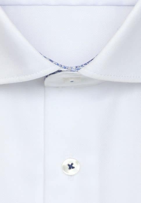 Close-up of a white dress shirt with a classic collar, a buttoned placket, and a white button with blue thread sewn in the centre. The shirt fabric appears smooth and neatly pressed.