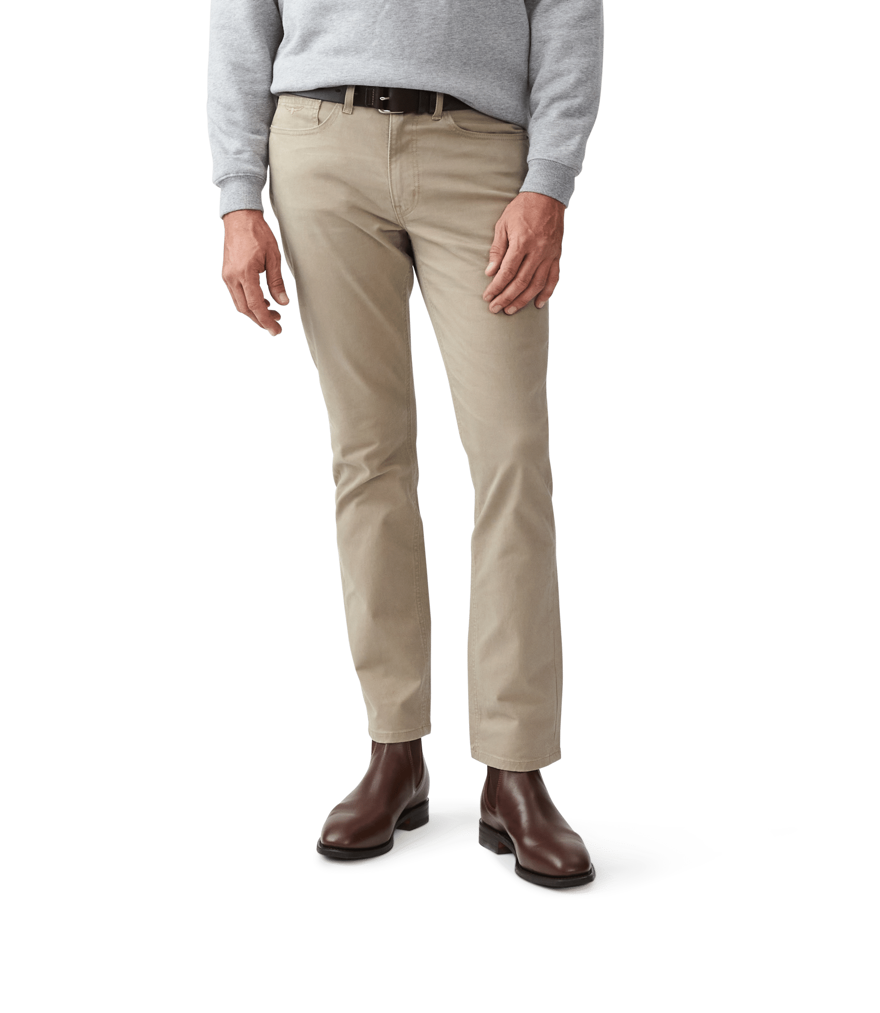 A person wearing light beige trousers, a grey jumper, and dark brown leather boots stands against a plain white background. The photo is cropped from the shoulders down.