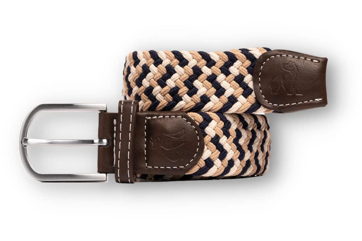 A woven belt with tan, navy, and beige strands, brown leather accents, and a silver buckle, displayed coiled on a white background.