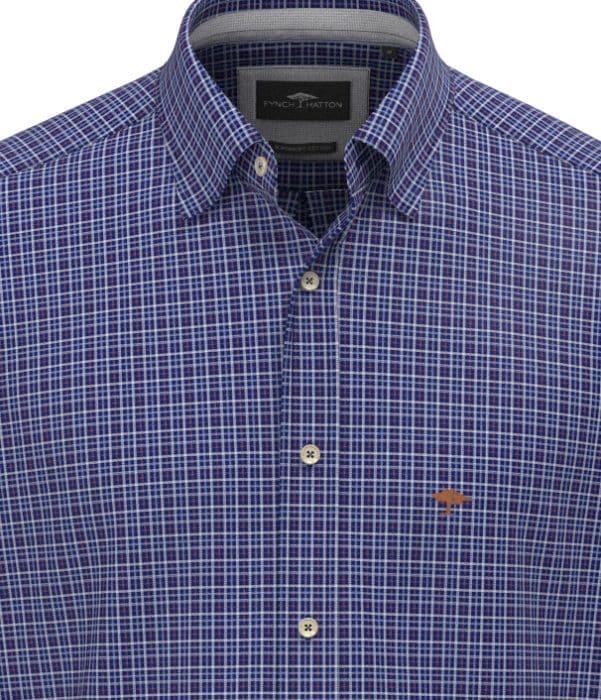 A close-up of a blue, white, and purple checked button-down shirt with a small embroidered logo on the left chest, shown on a mannequin or flat surface.