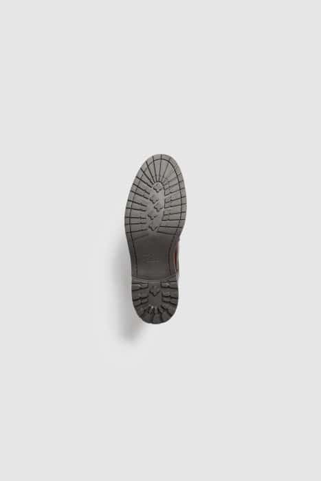 A single brown shoe shown from the bottom, displaying its textured, rugged sole against a plain white background.