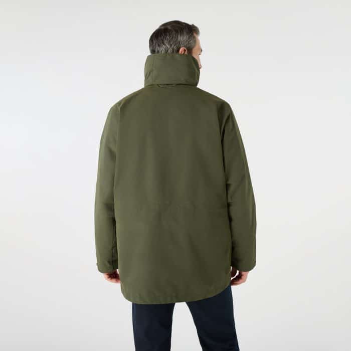 A man seen from behind wearing an olive green hooded parka jacket and dark trousers.