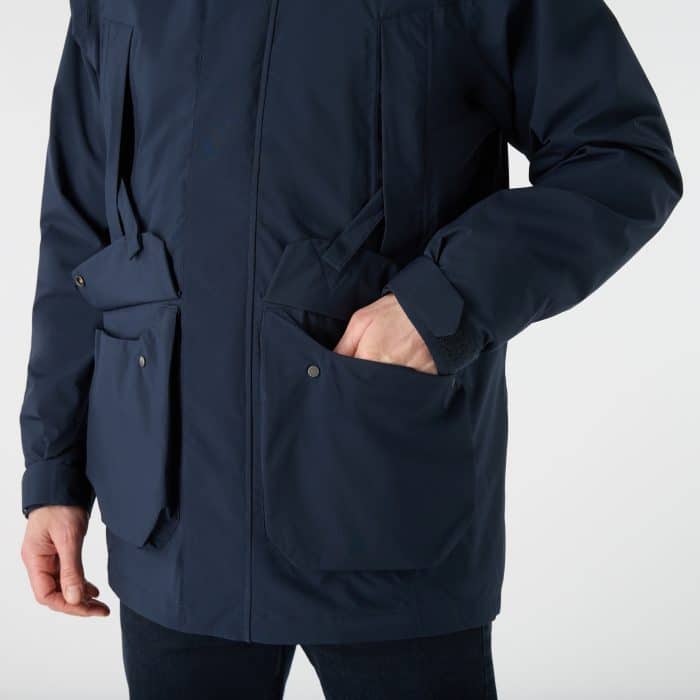 A person wearing a navy blue utility jacket with multiple large front pockets, one of which contains a hand.
