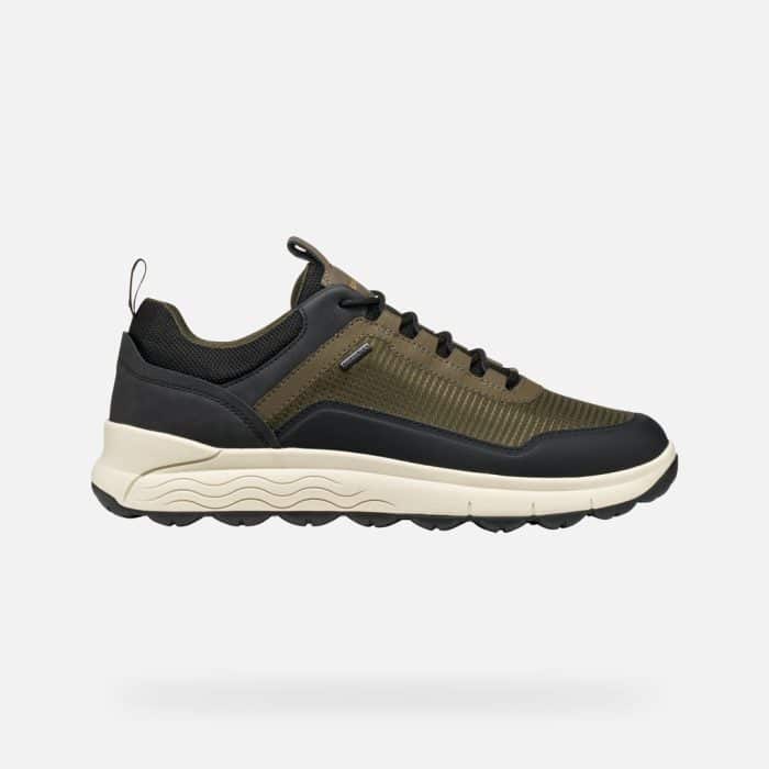Olive green and black low-top trainer with a thick, wavy-textured white midsole and a black lugged outsole.