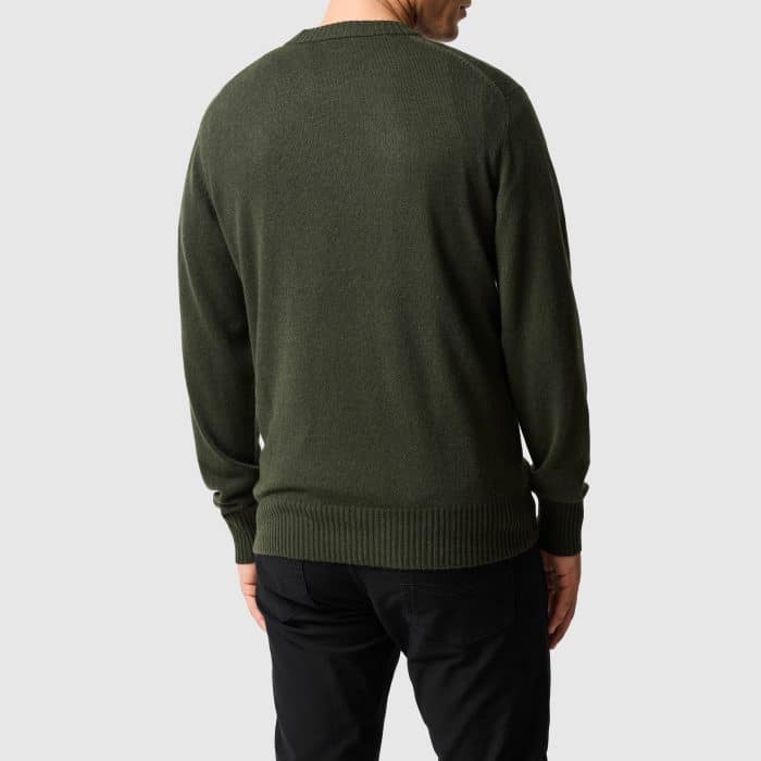 A person from behind wearing a dark green jumper and black trousers.