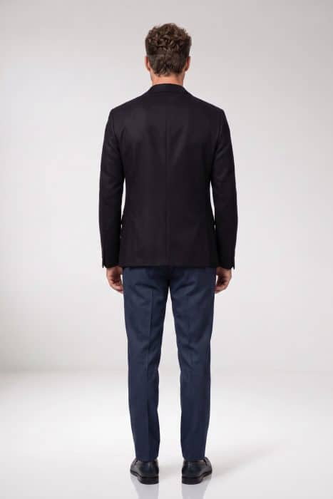 A man seen from behind wearing a black suit jacket and navy blue trousers.
