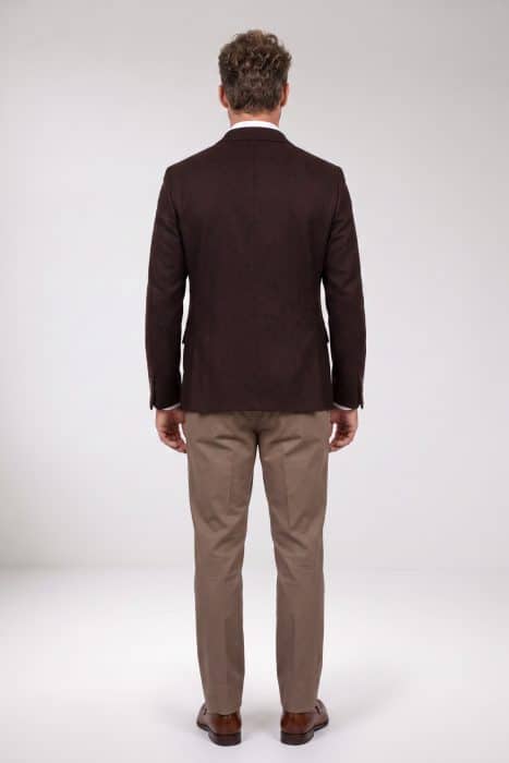 Back view of a man wearing a brown blazer, white dress shirt, tan trousers, and brown leather loafers.
