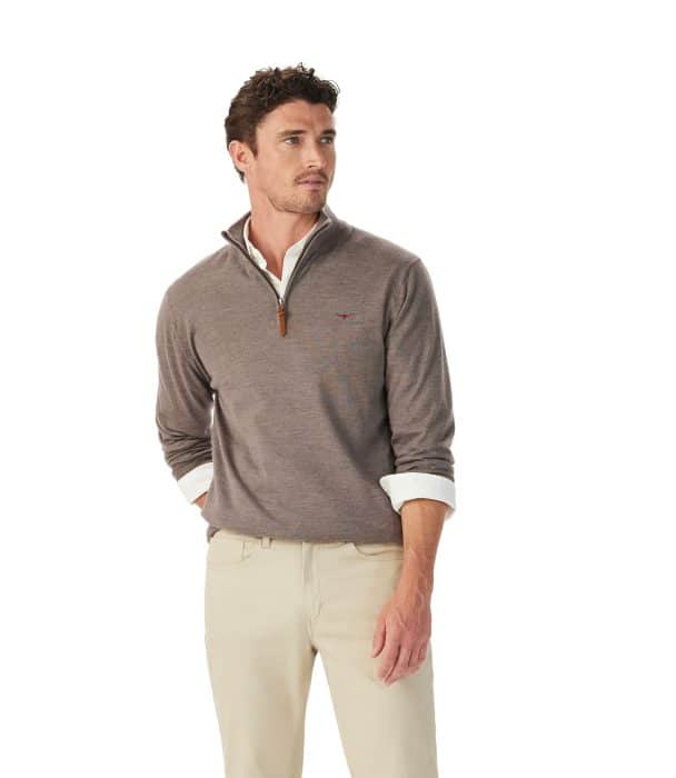 A man wearing a taupe quarter-zip jumper over a white collared shirt with beige trousers.